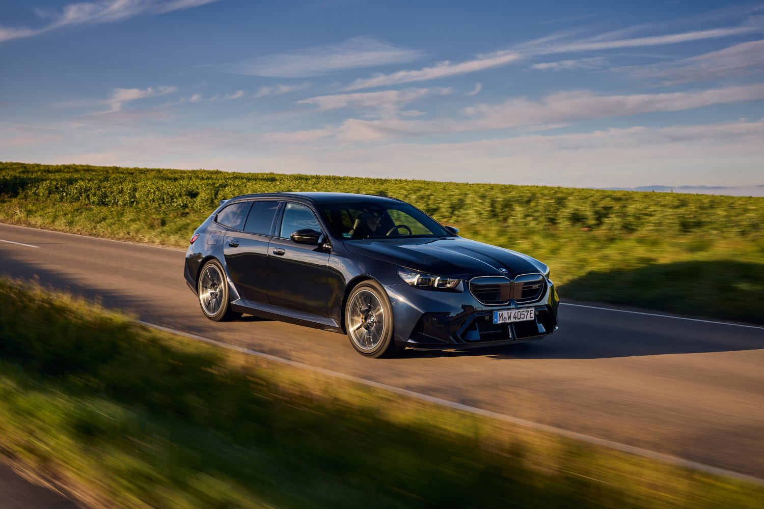 The new BMW M5 Touring driving fast along country roads.