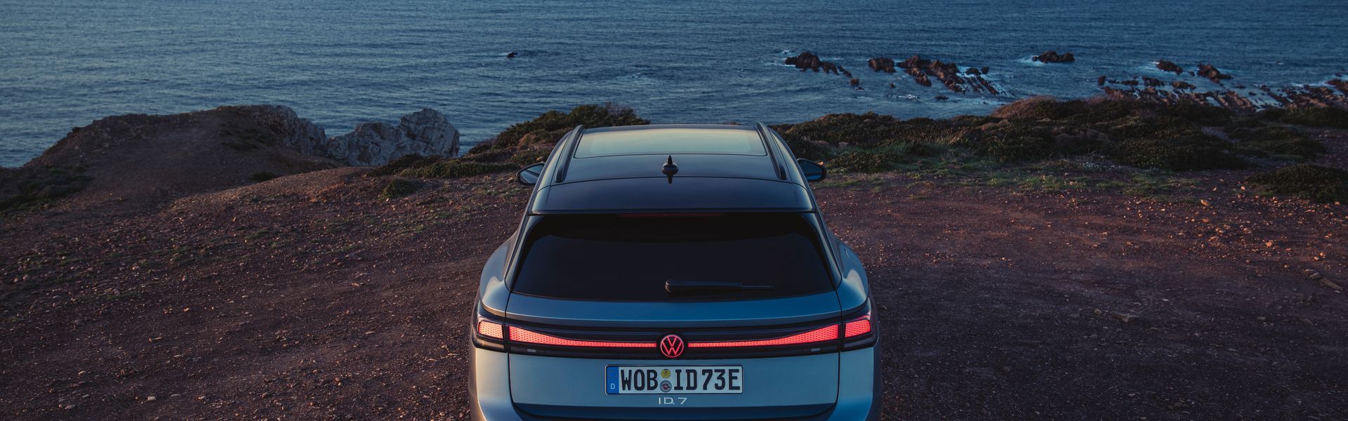 All new Volkswagen ID.7 in grey parked by cliff edge by sea