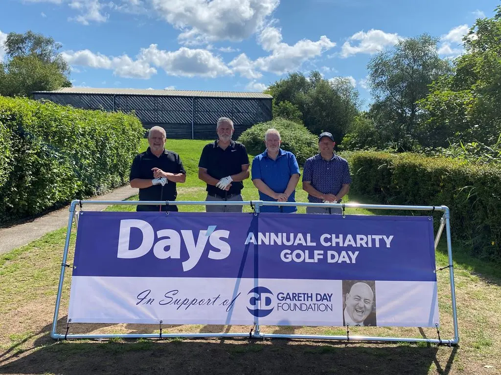 4 Men stood in front of Day's Annual Charity Golf Day banner