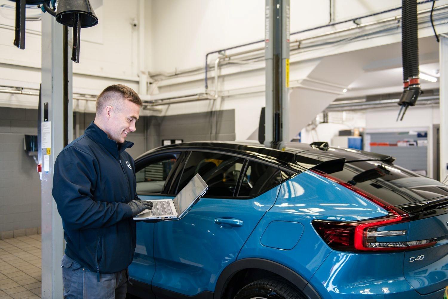 At Agnew Belfast Volvo repair centre, Volvo Mechanic inspects used Volvo C40 Recharge with laptop during MOT preparation