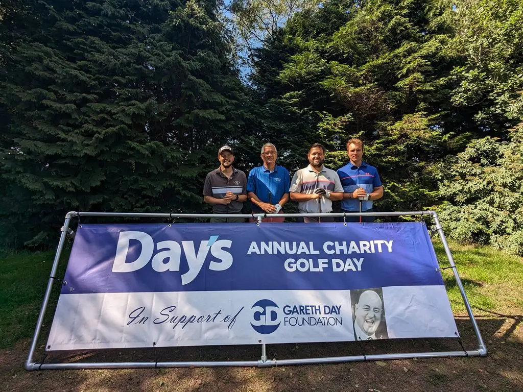 4 Men stood in front of Day's Annual Charity Golf Day banner