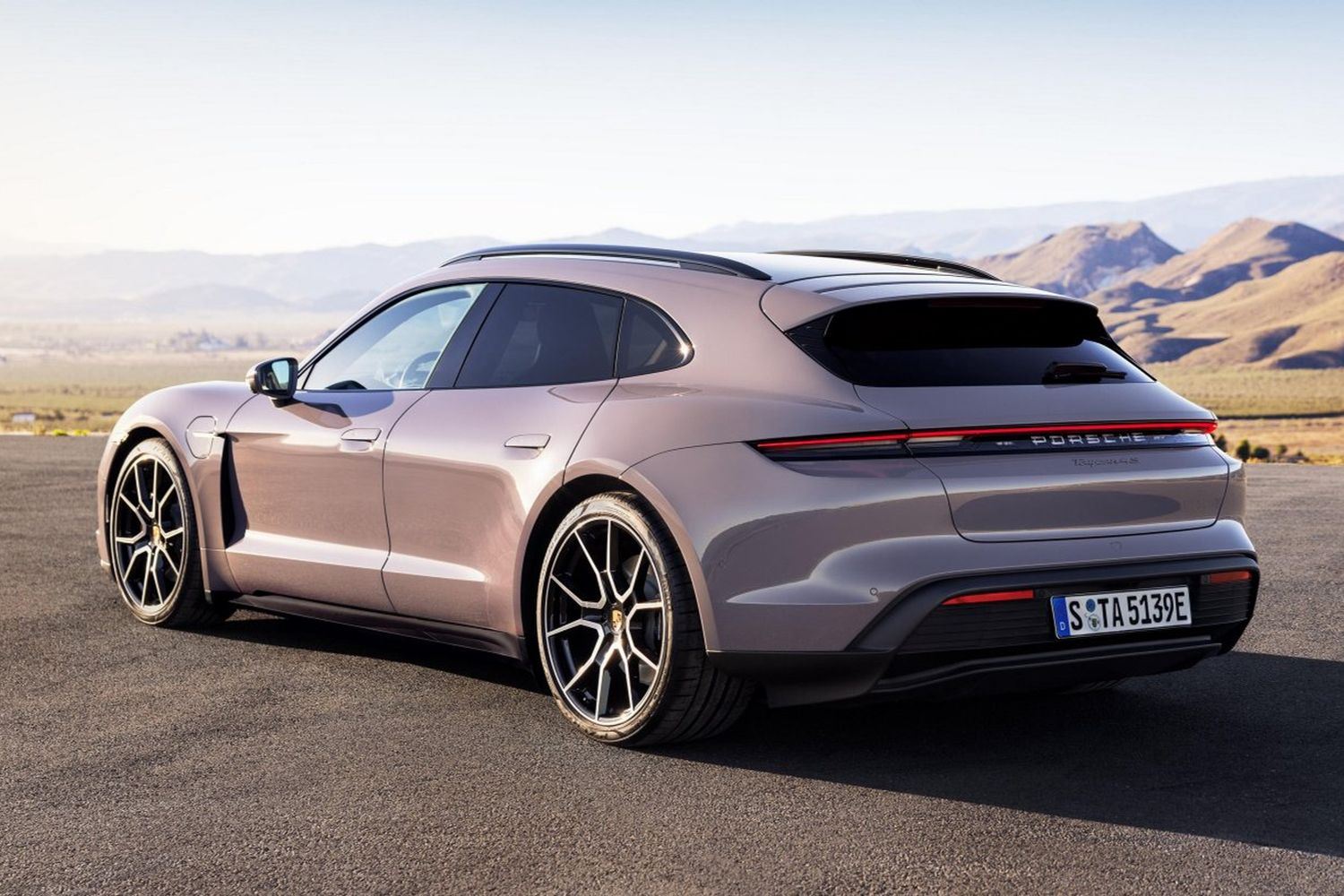 Rear view of the new Porsche Taycan in purple, parked with mountain view behind