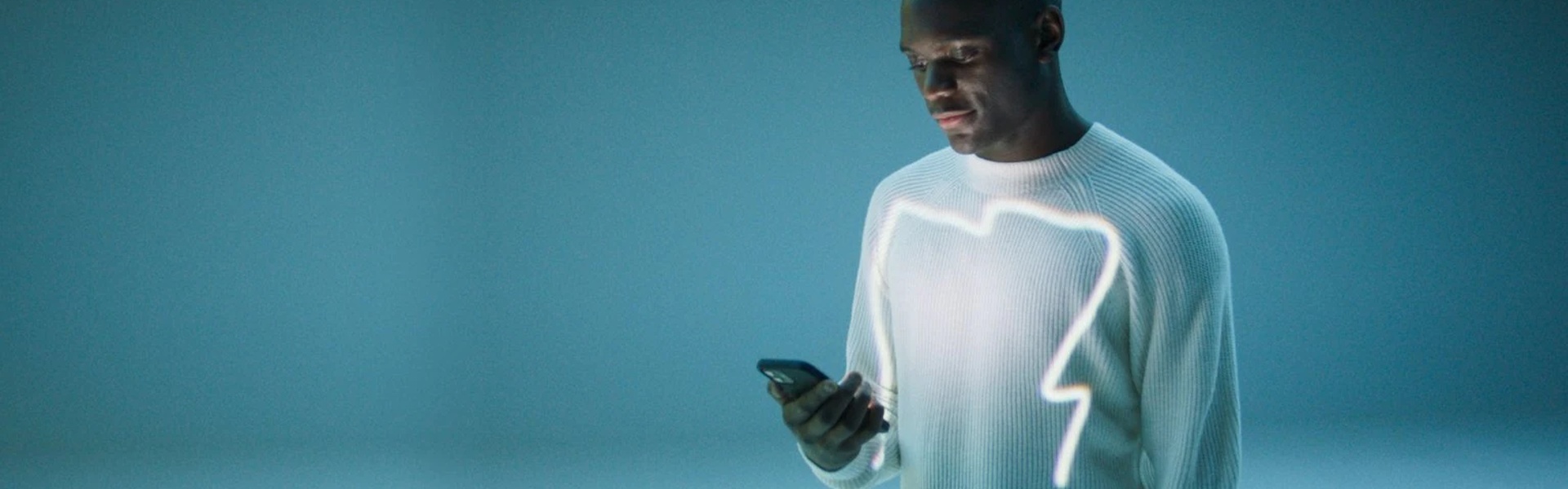 Person on neutral blue background, uses Mercedes me connect on mobile phone to find out more about their Mercedes-Benz