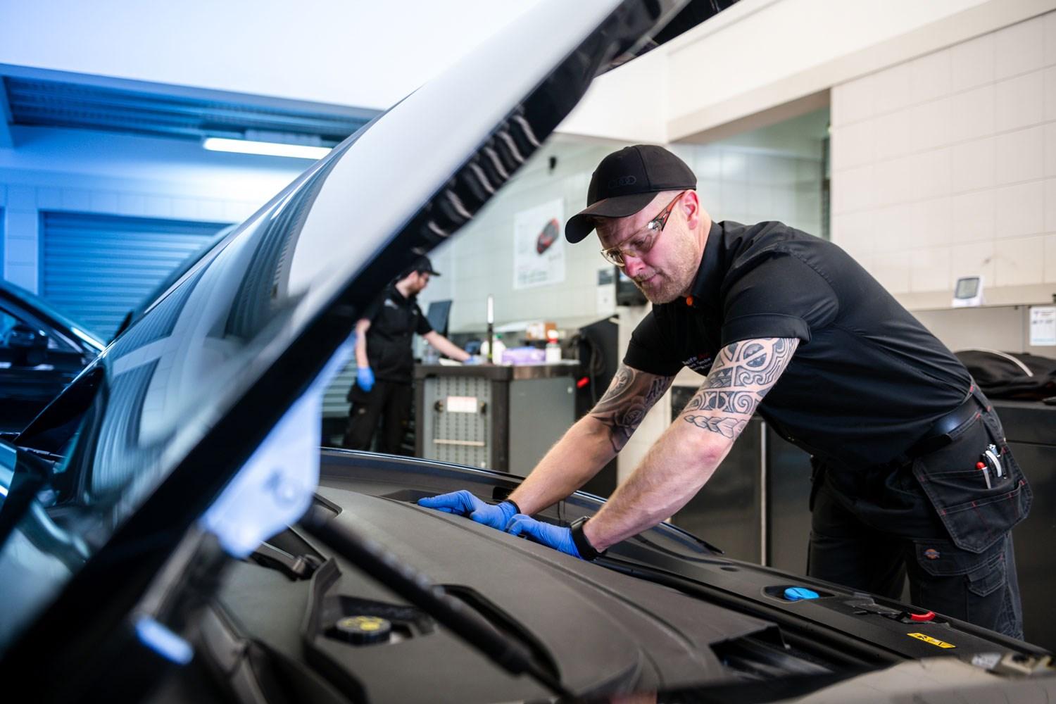 Audi Repair Specialist inspects under the hood of car during routine maintenance at the Audi Repair Centre at Belfast Audi