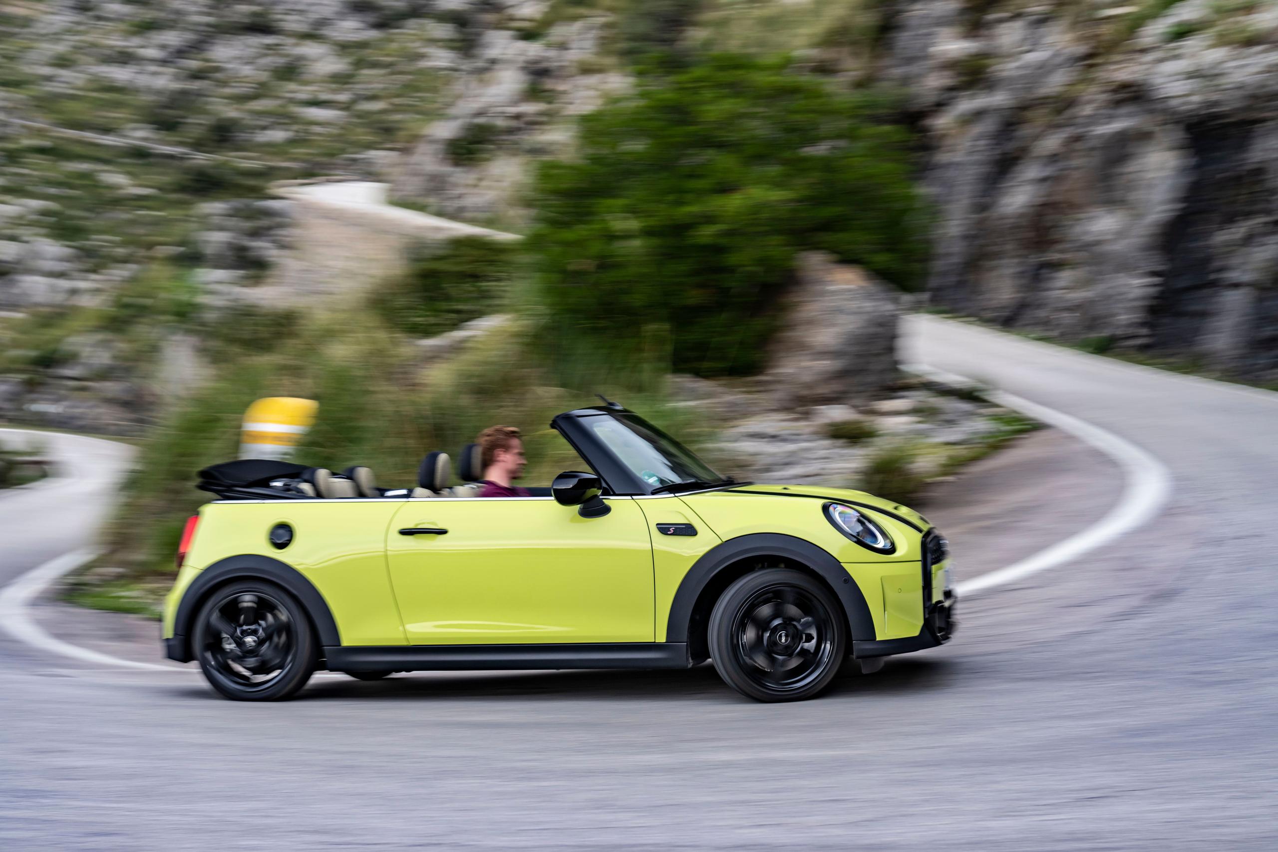 Side view of the new MINI Convertible in yellow, driving up mountain road