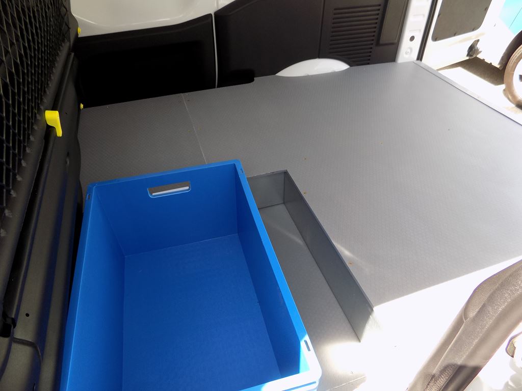 Van load area with raised floor platform and blue storage crate in the cargo space.