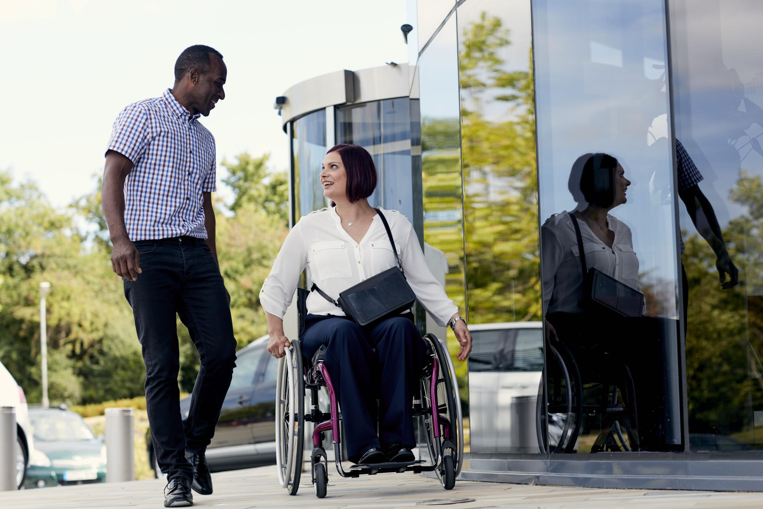 Woman in wheelchair speaks to man as they go into work