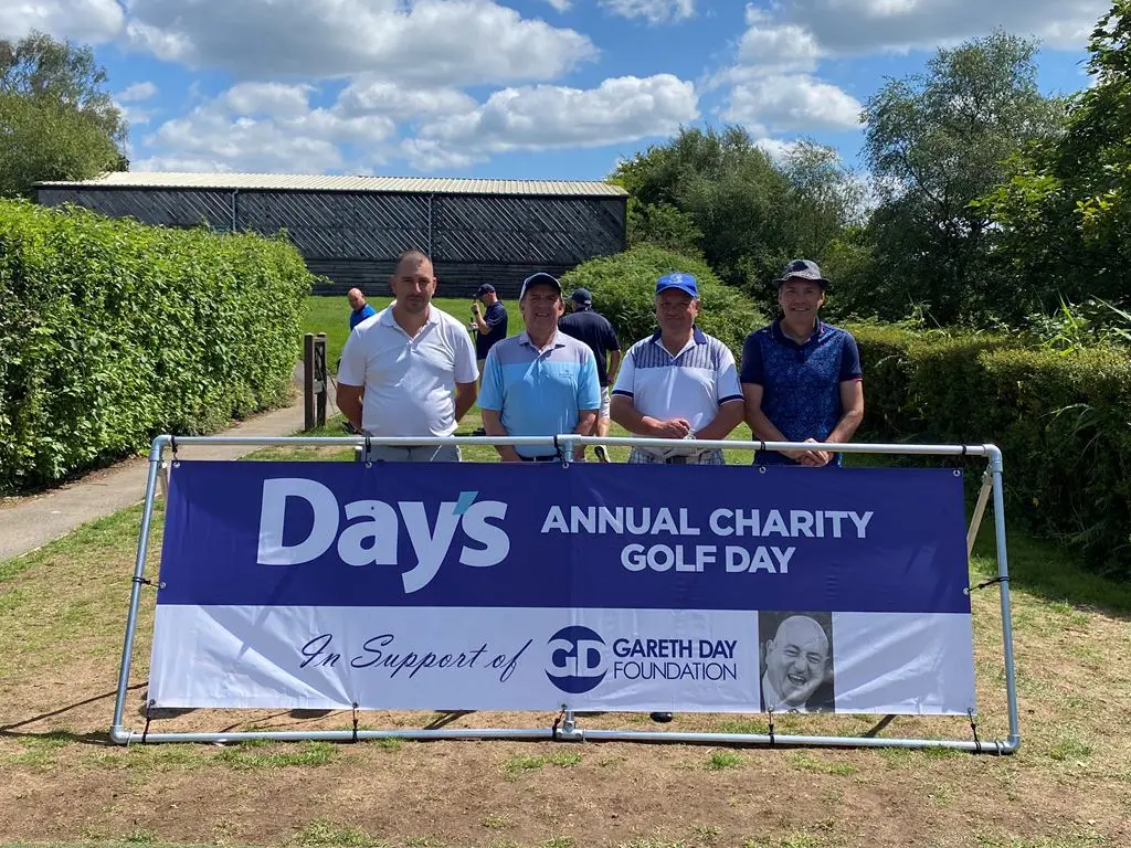 4 Men stood in front of Day's Annual Charity Golf Day banner