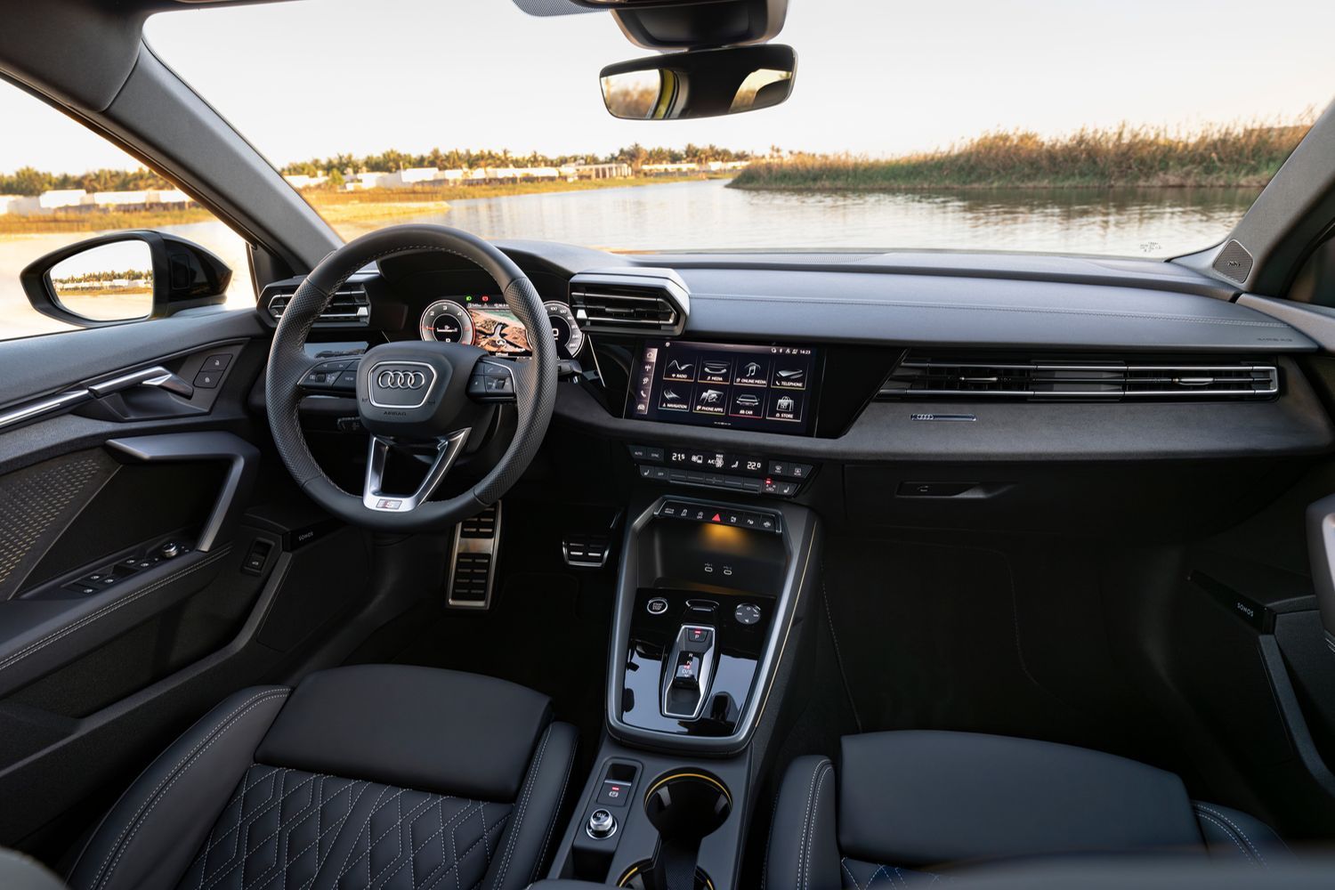 New Audi A3 Sportback (2024) interior, parked in front of lake. The interior highlights the main console and front and rear passenger seats.