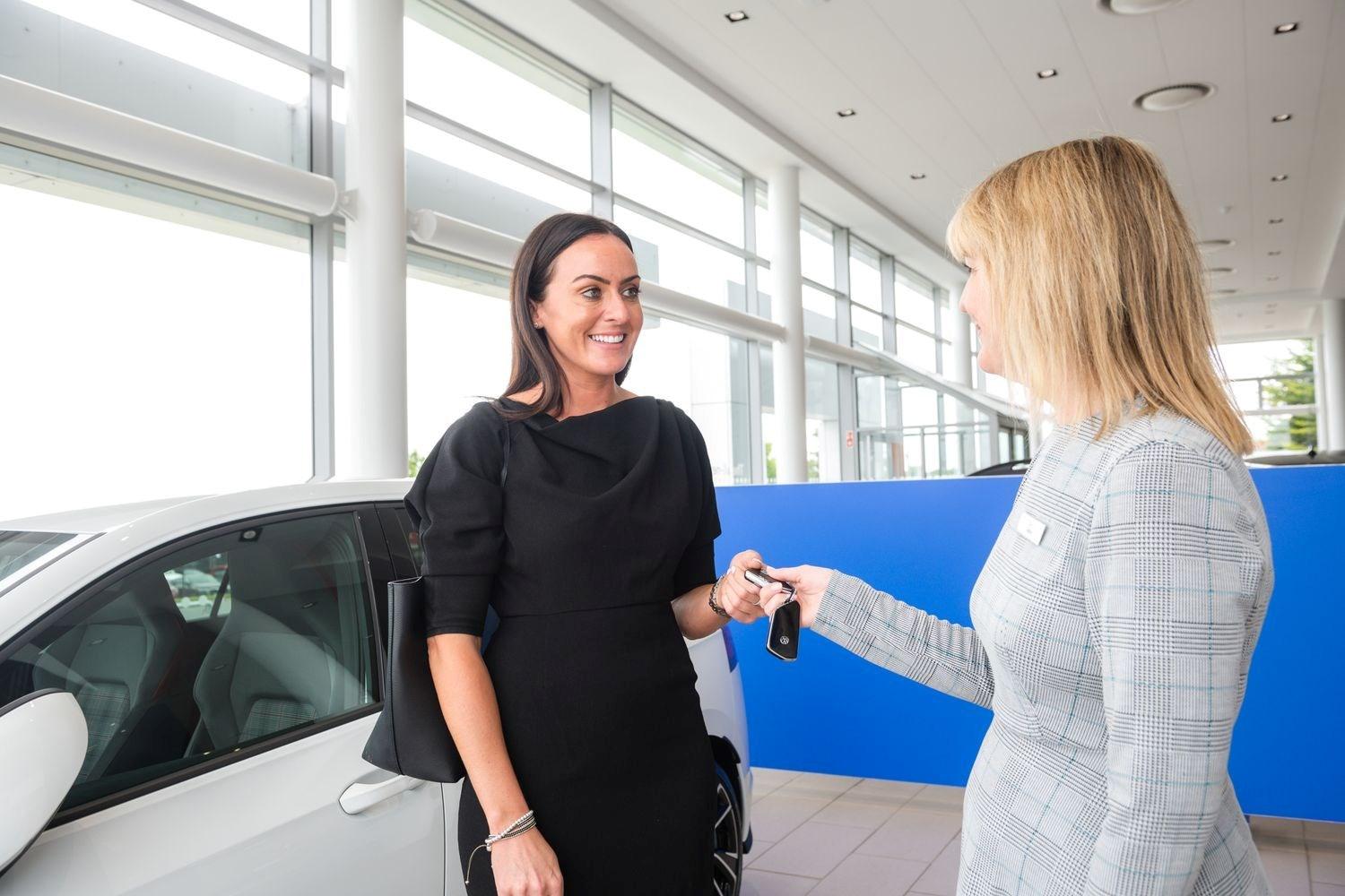Volkswagen Sales Specialist hands over new Volkswagen Golf keys to smiling customer