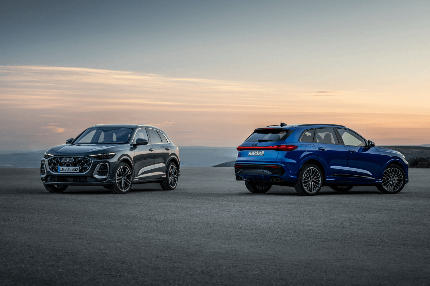 Front view of a grey Audi Q5 and rear view of a blue Audi Q5.