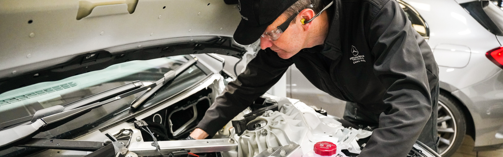 Mercedes-Benz Technician inspects under the hood of vehicle for repair during Premium Servicing work.