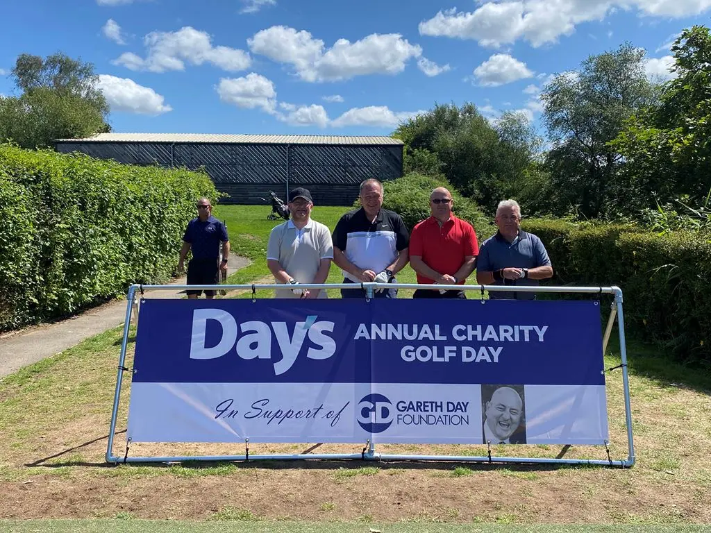 4 Men stood in front of Day's Annual Charity Golf Day banner