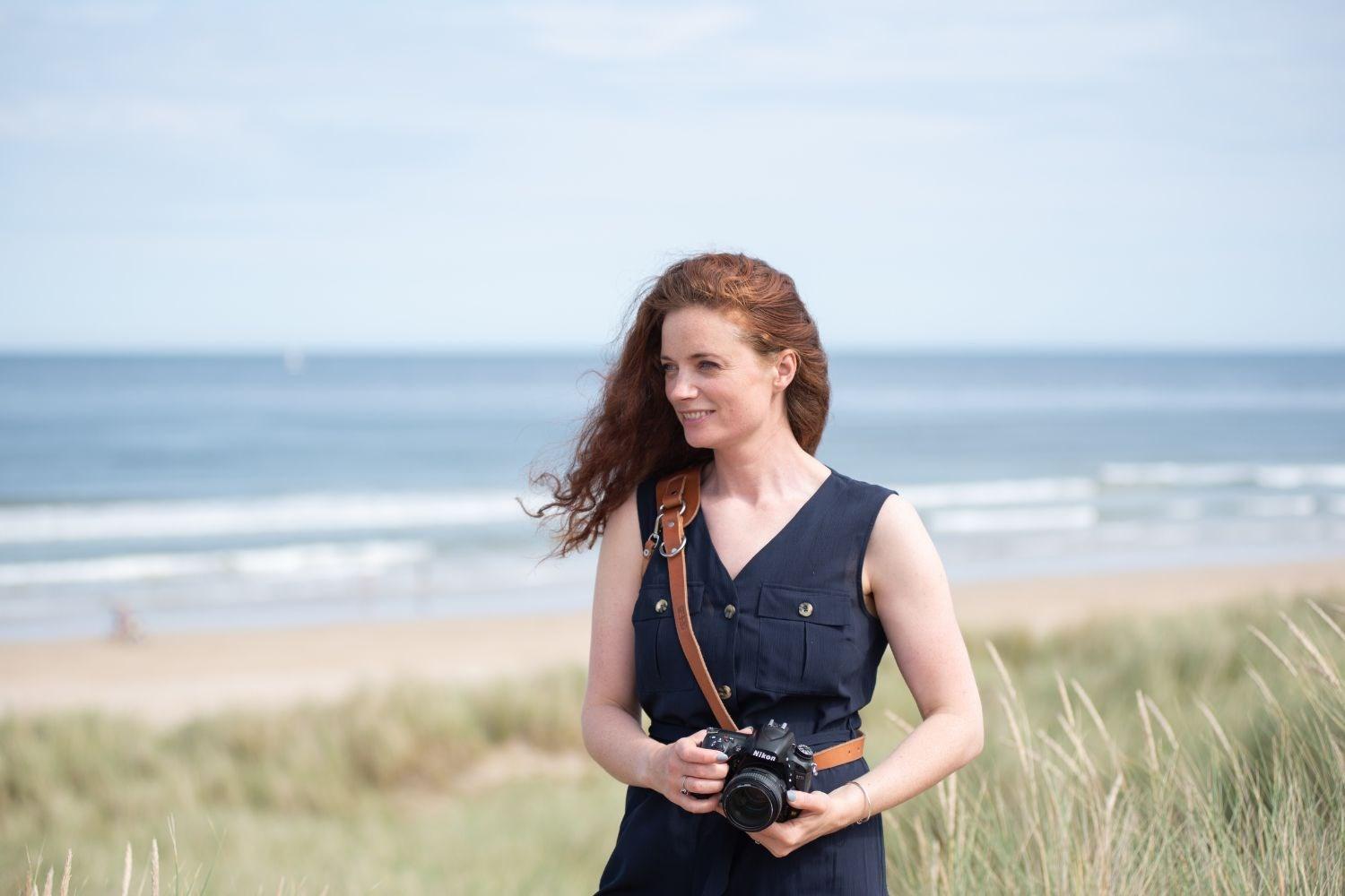 Photographer, Collette O’Neill, holding her camera at the beach