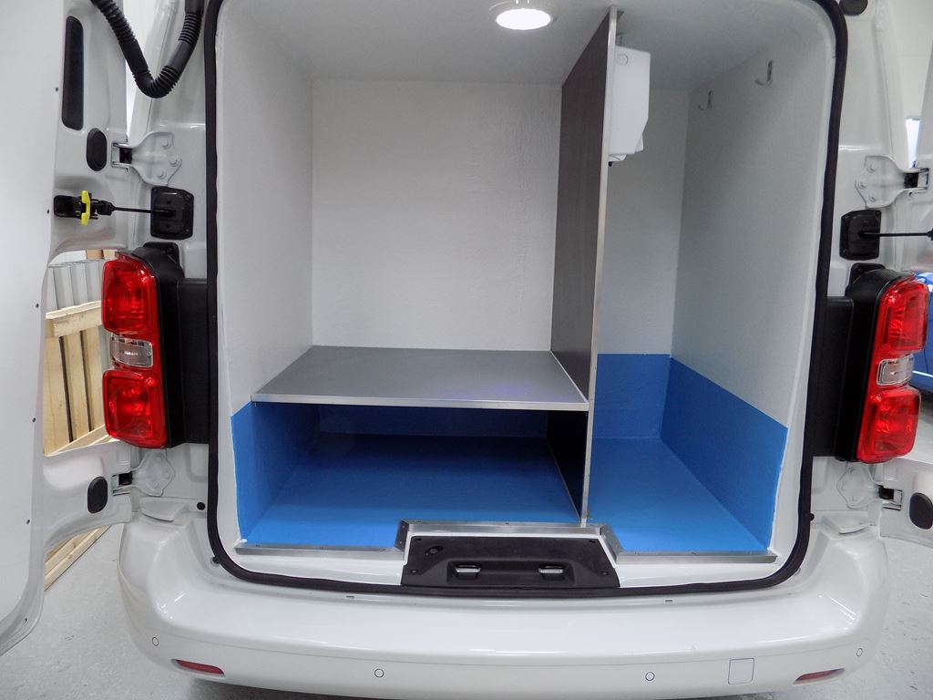 Van cargo area with blue floor lining, raised platform and partitioned storage section.