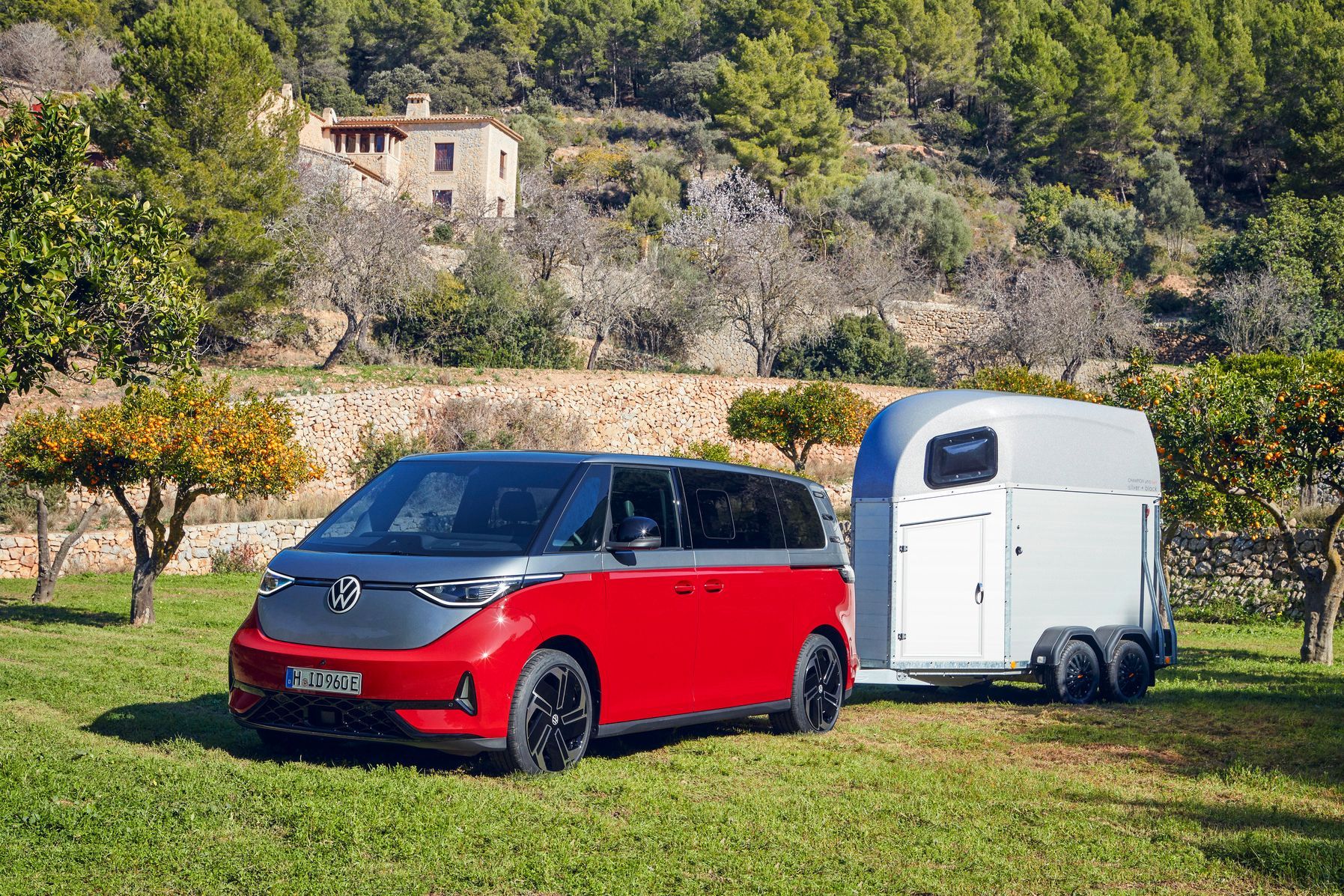 Volkswagen ID.Buzz GTX, in red, parked in Italian countryside with trailer attached.