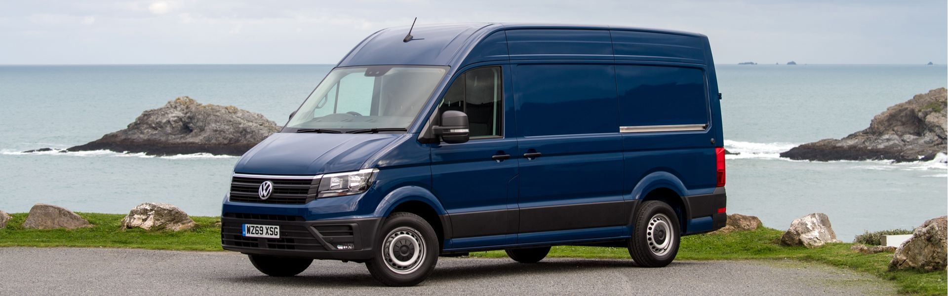 Blue Volkswagen Crafter Panel van Commerce parked by the sea.