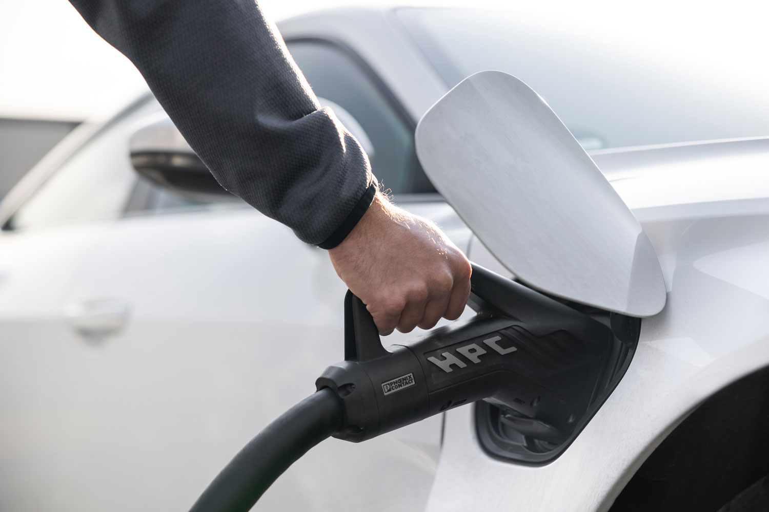 Person plugs vehicle into HPC electric charging station