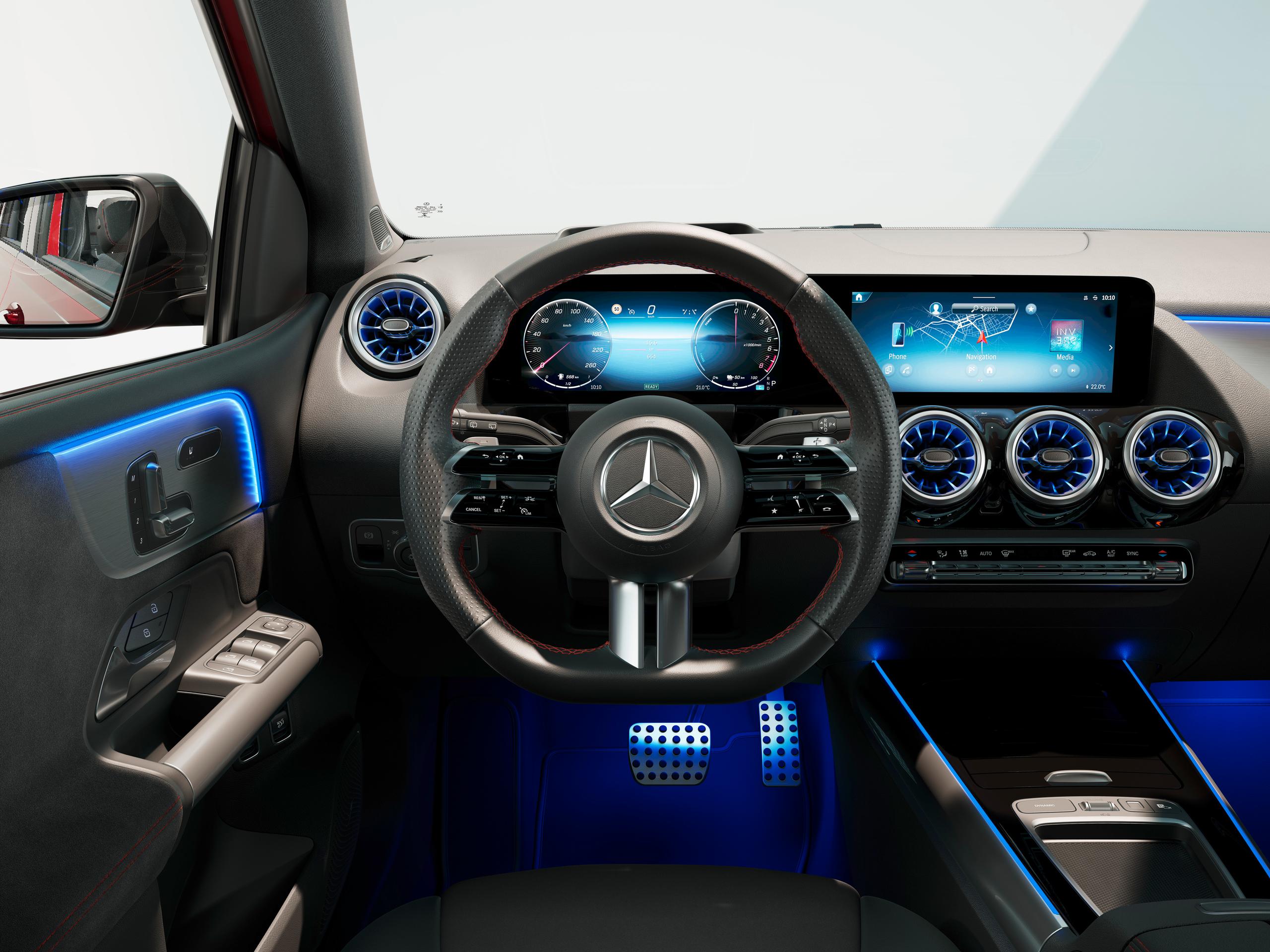 Mercedes-Benz A-Class Hatchback Interior with blue LED lights, a black steering wheel with red stitching and dual infotainment displays.