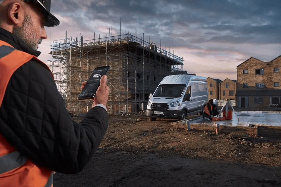 Constrution worker on Ford app with silver Ford in the background on construction site