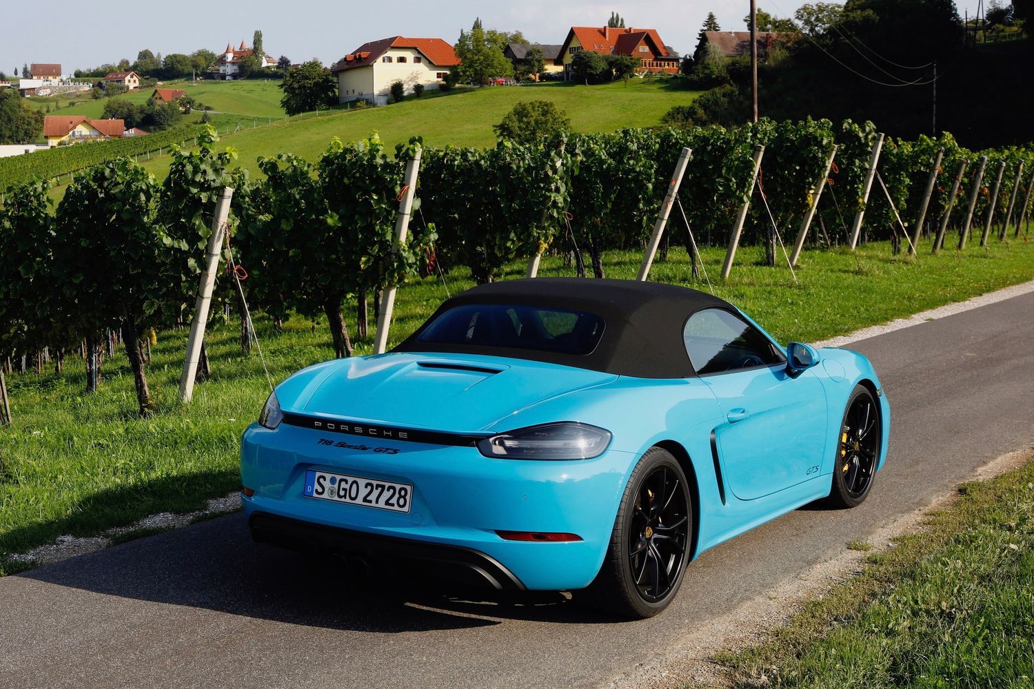 Rear view of the new Porsche 718 in view, driving through Italian vineyards