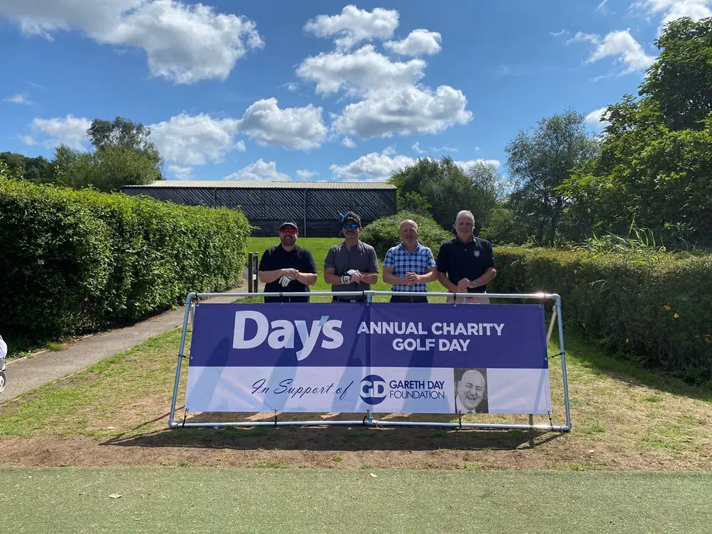 4 Men stood in front of Day's Annual Charity Golf Day banner