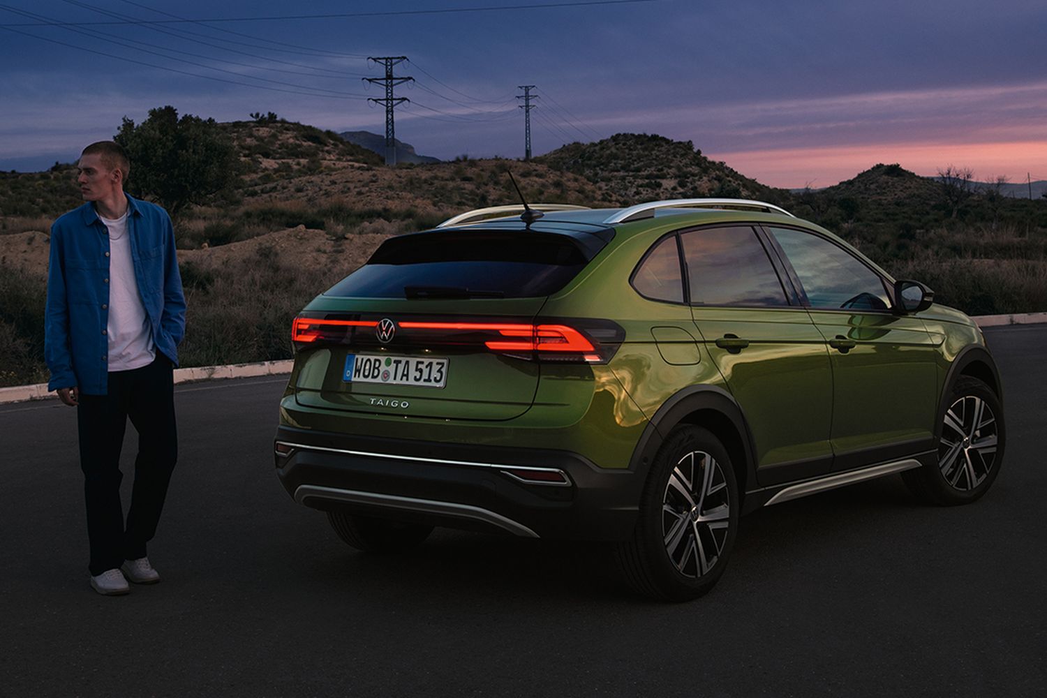 Rear and side view of the new Volkswagen Taigo in green, with a sunset and hill view behind