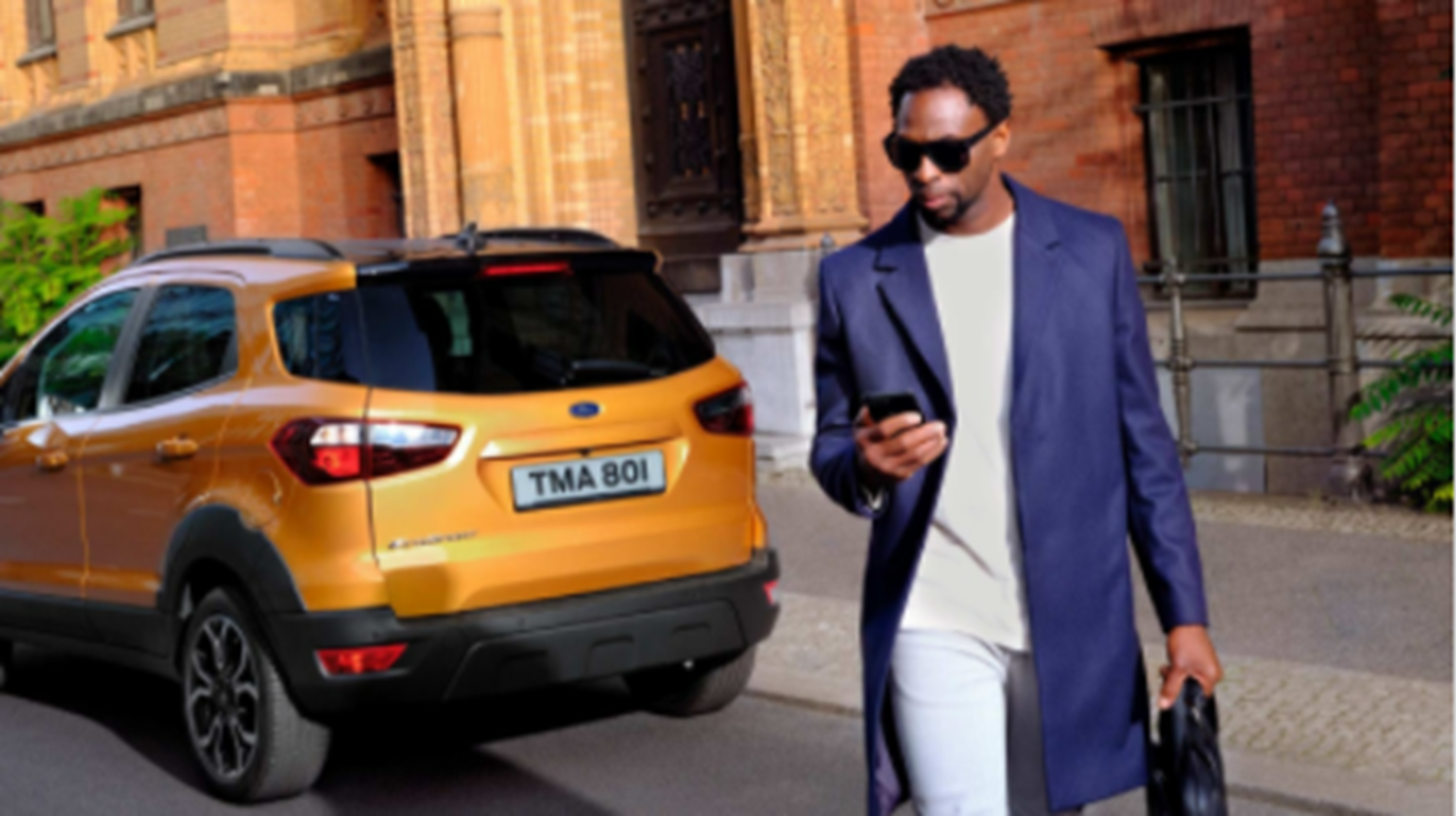 Man walking away from Orange Ford whilst looking at his phone