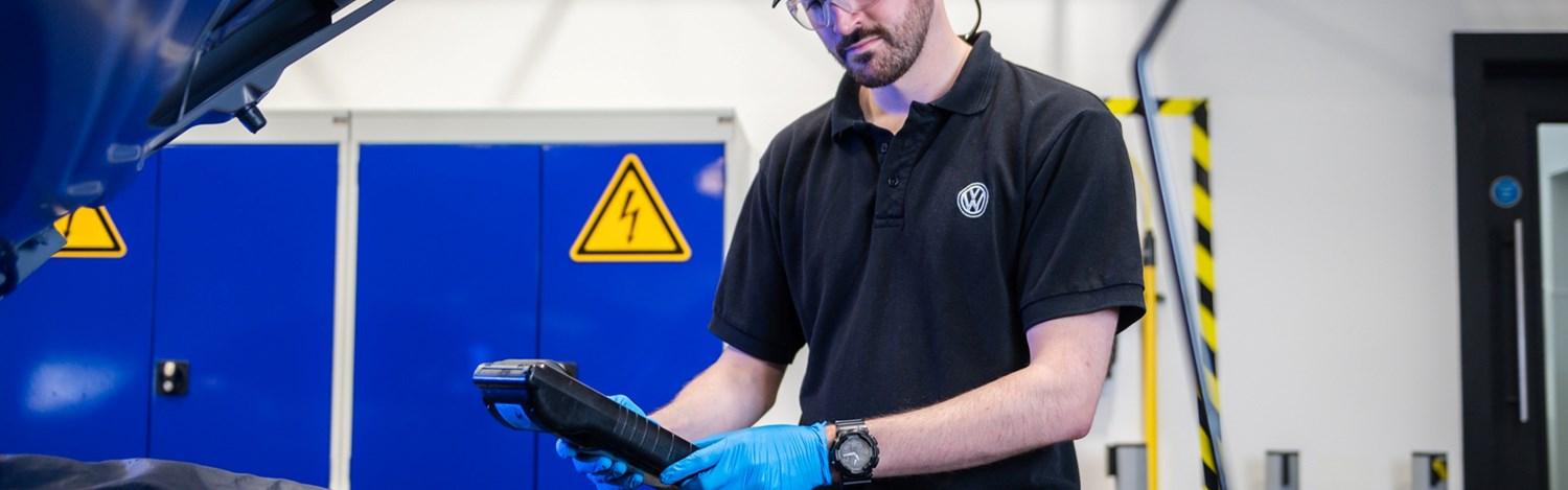 Volkswagen Repair Specialists inspects car battery of used Volkswagen Golf during routine maintenance at the Volkswagen Approved Accident Repair Centre in Agnew Volkswagen Belfast