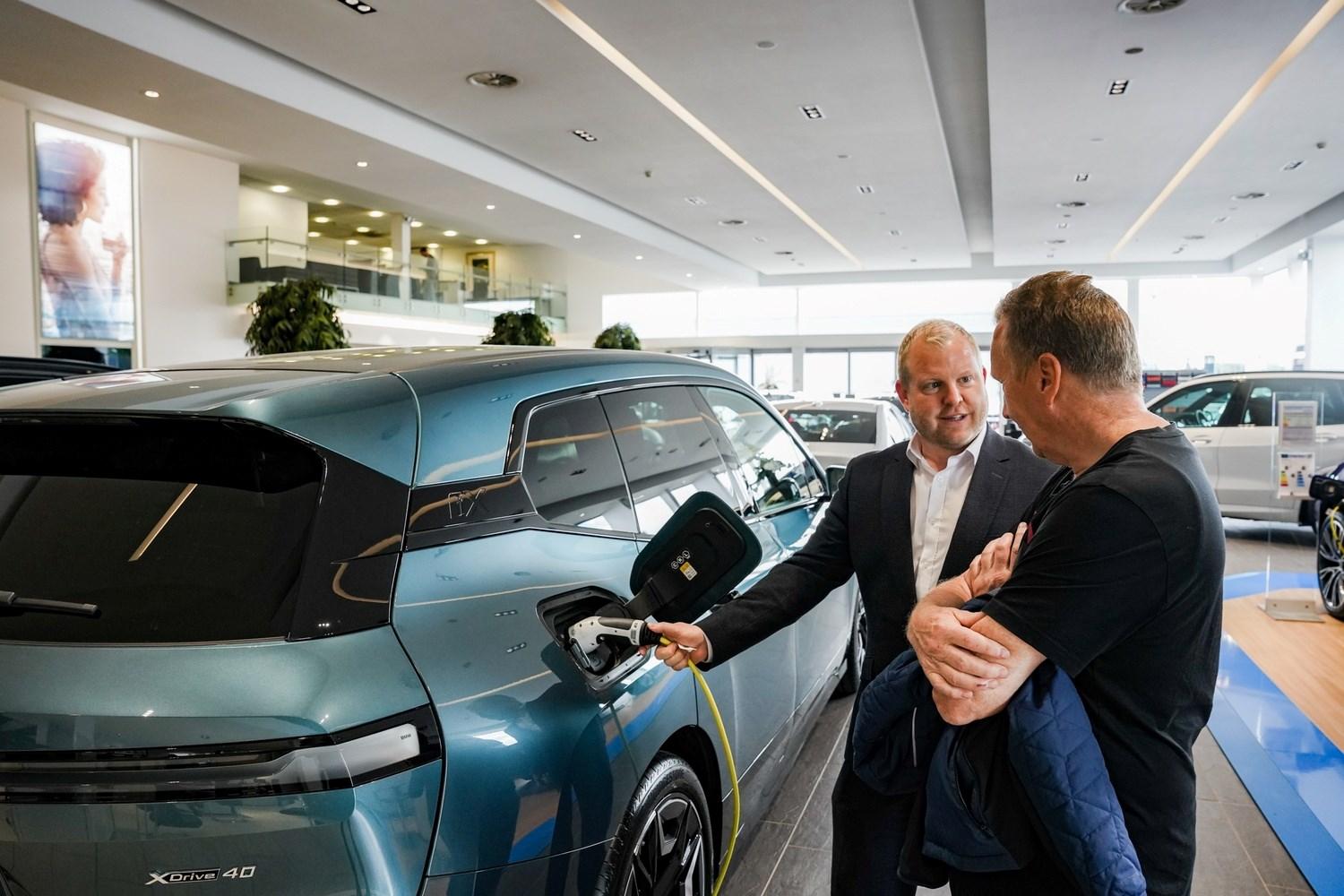 BMW Sales Manager talks to a customer about the benefits of going electric while demonstrating with a BMW iX at the Bavarian BMW showroom