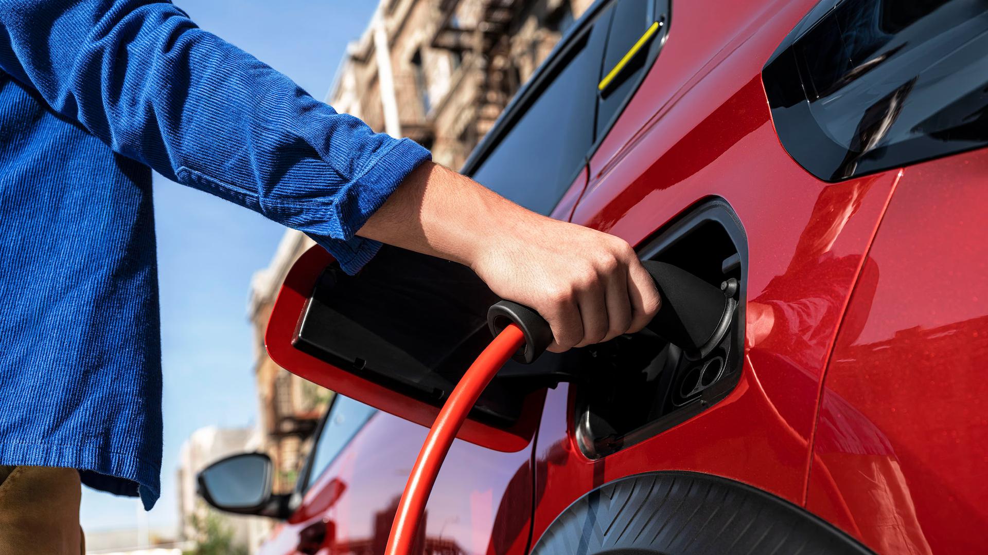Plugging a charging cable into a red Citroen E-C3