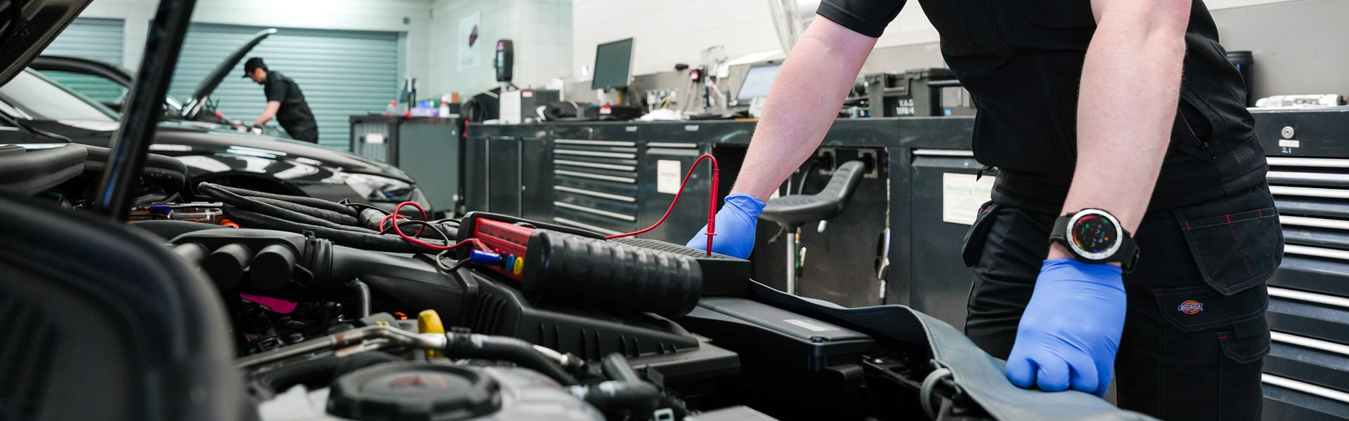 Volkswagen Repair Specialist stands over engine during routine maintenance to check for faults