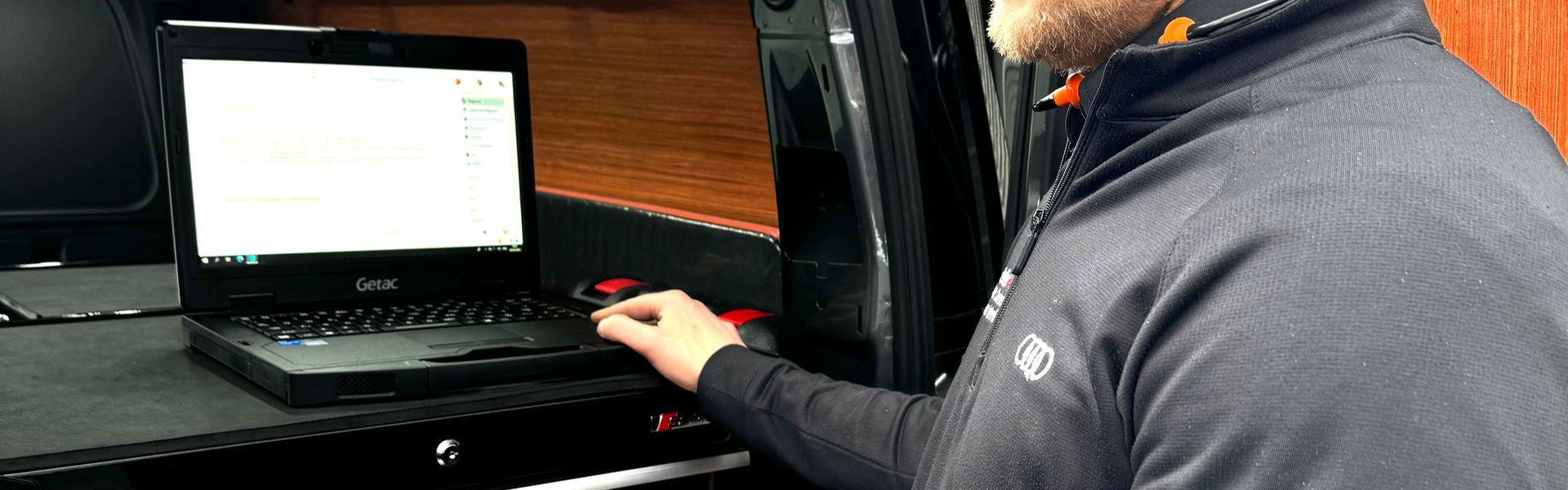 Audi Mobile Technician checks laptop for maintenance work at customers home