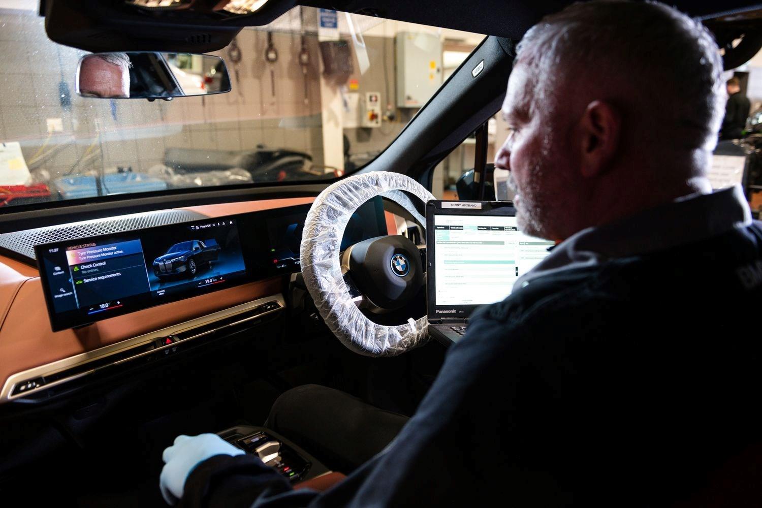 BMW Technician sits in driver seat to check information on the infotainment system during service at Bavarian BMW Belfast