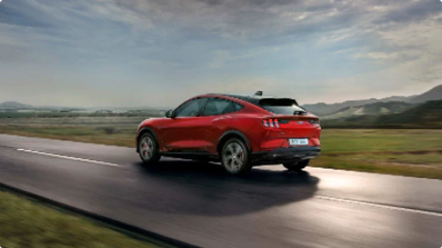 Red Ford driving down road