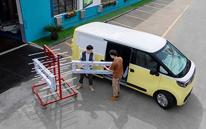 Yellow and white Maxus eDeliver 5 parked beside two workers loading materials through the side door