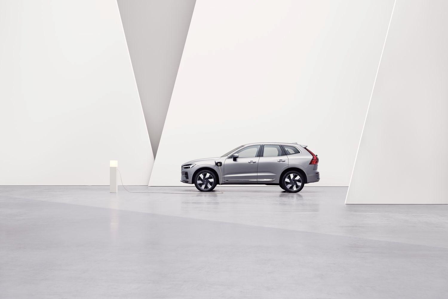 Side view of the new Volvo XC60 Recharge in silver, parked by charging station