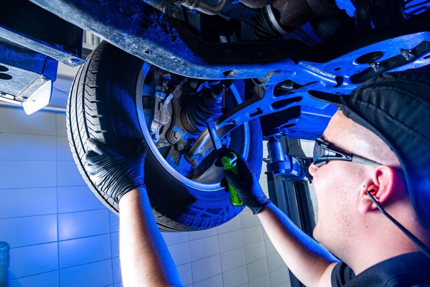 Volkswagen Commercials Technician inspects the wheel of a Volkswagen Caddy with a blue light at the Volkswagen Approved Repair Centre, Agnew Van Centre, Mallusk, Northern Ireland.