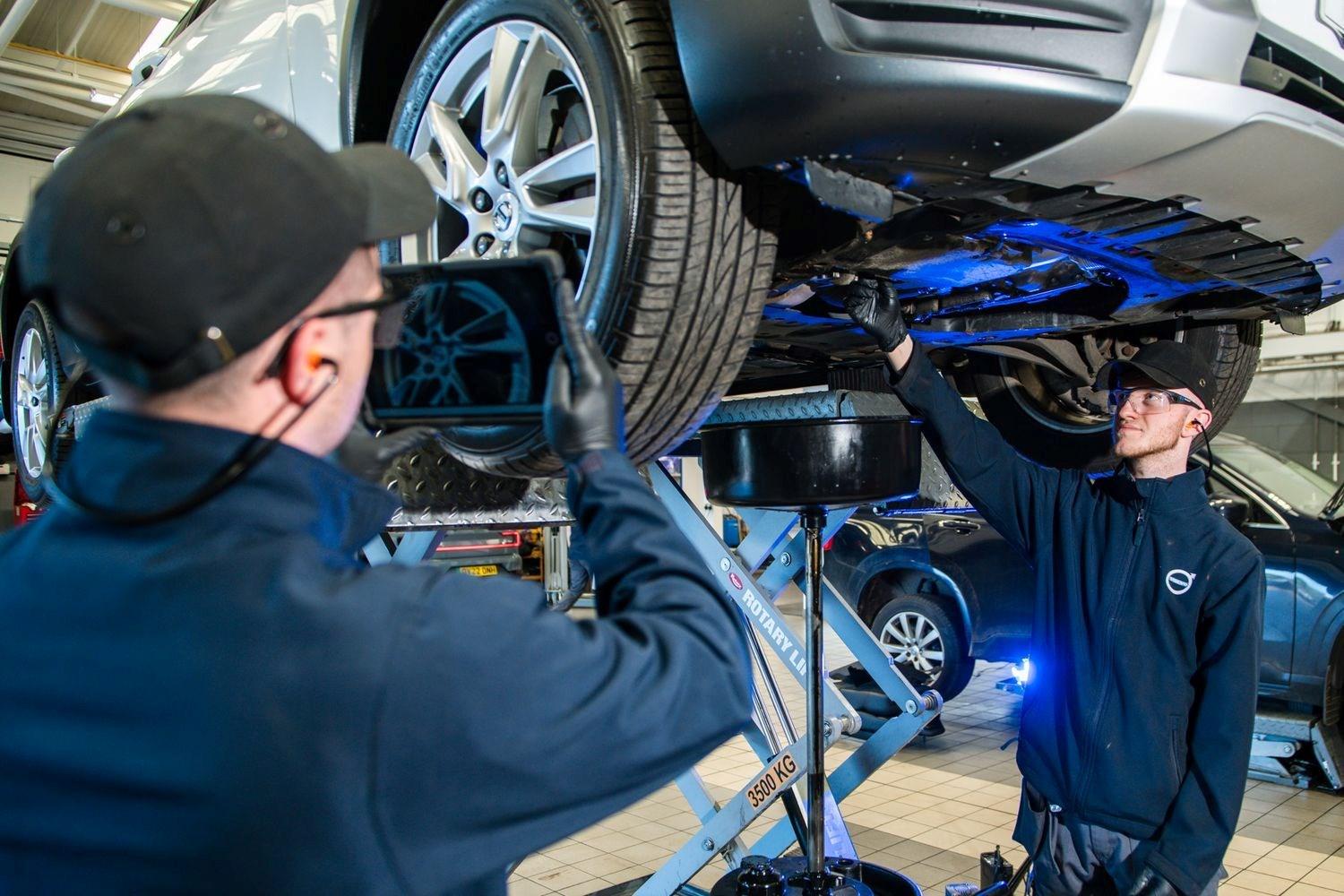 At the repair centre in Agnew Belfast Volvo, two Volvo mechanics inspect the wheel alignment of used car during Volvo Health Check