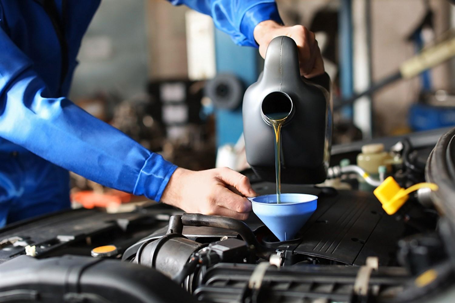 Volkswagen Service Specialist changes brake fluid by pouring fluid into vehicle during maintenance at Volkswagen Approved Repair Centre at Agnew Van Centre, Mallusk