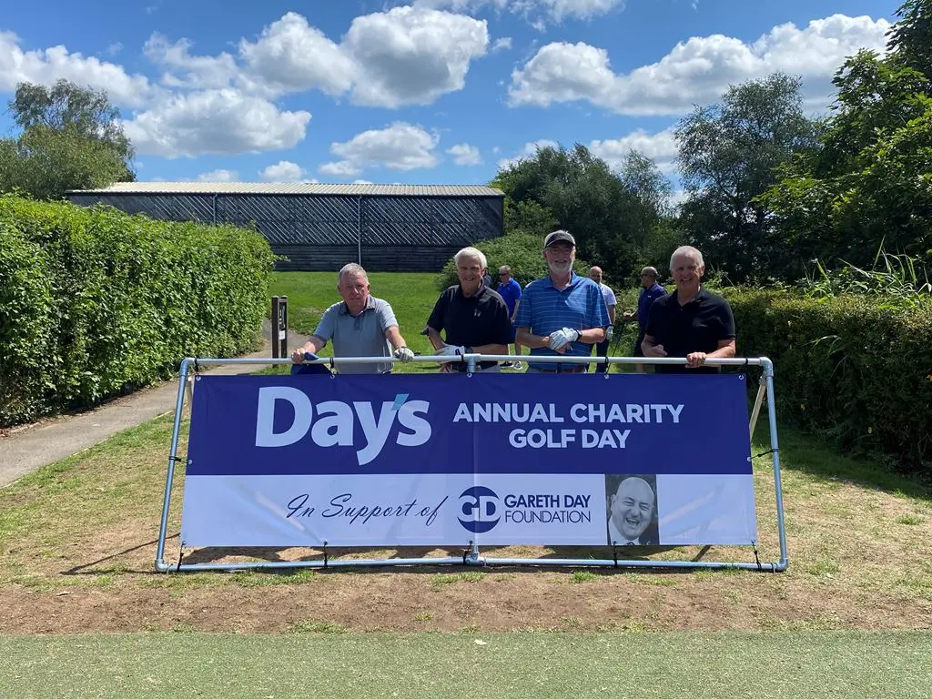 4 Men stood in front of Day's Annual Charity Golf Day banner