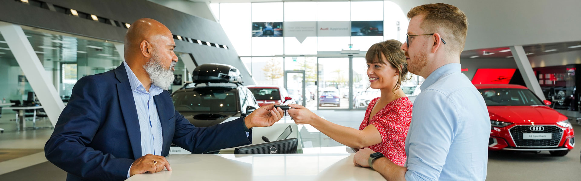 Audi Sales Specialist hands over keys of a brand new Audi A3 to customers in the Audi showroom at Portadown Audi