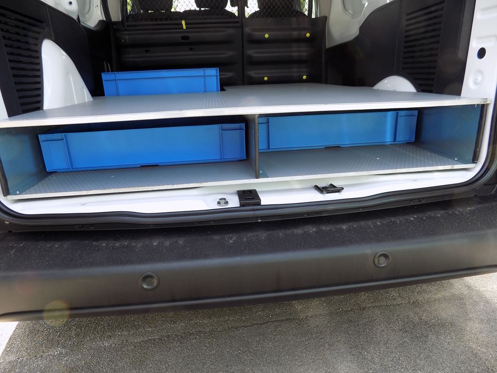 Van rear storage platform with open compartments and blue storage crates underneath.