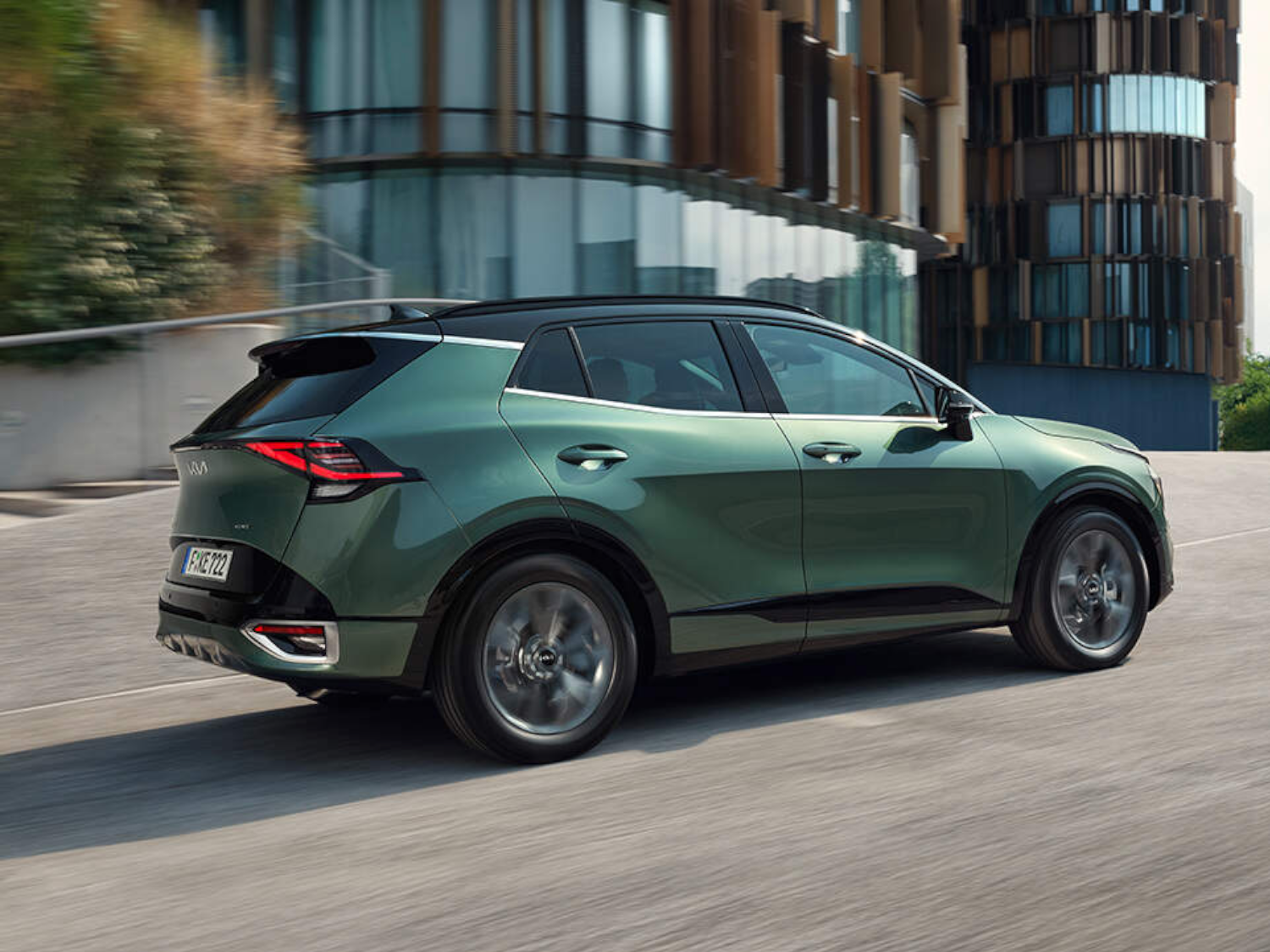 Green Kia Sportage parked by buildings