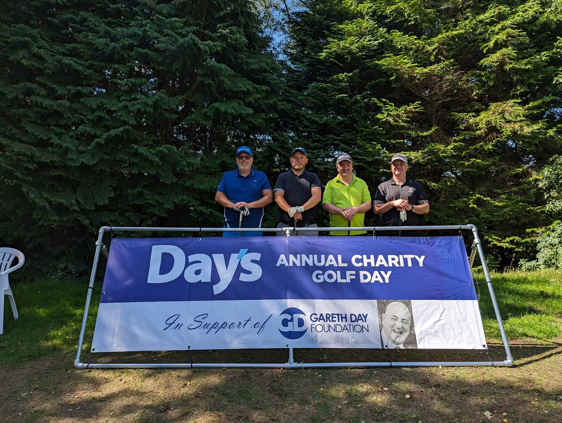 4 Men stood in front of Day's Annual Charity Golf Day banner