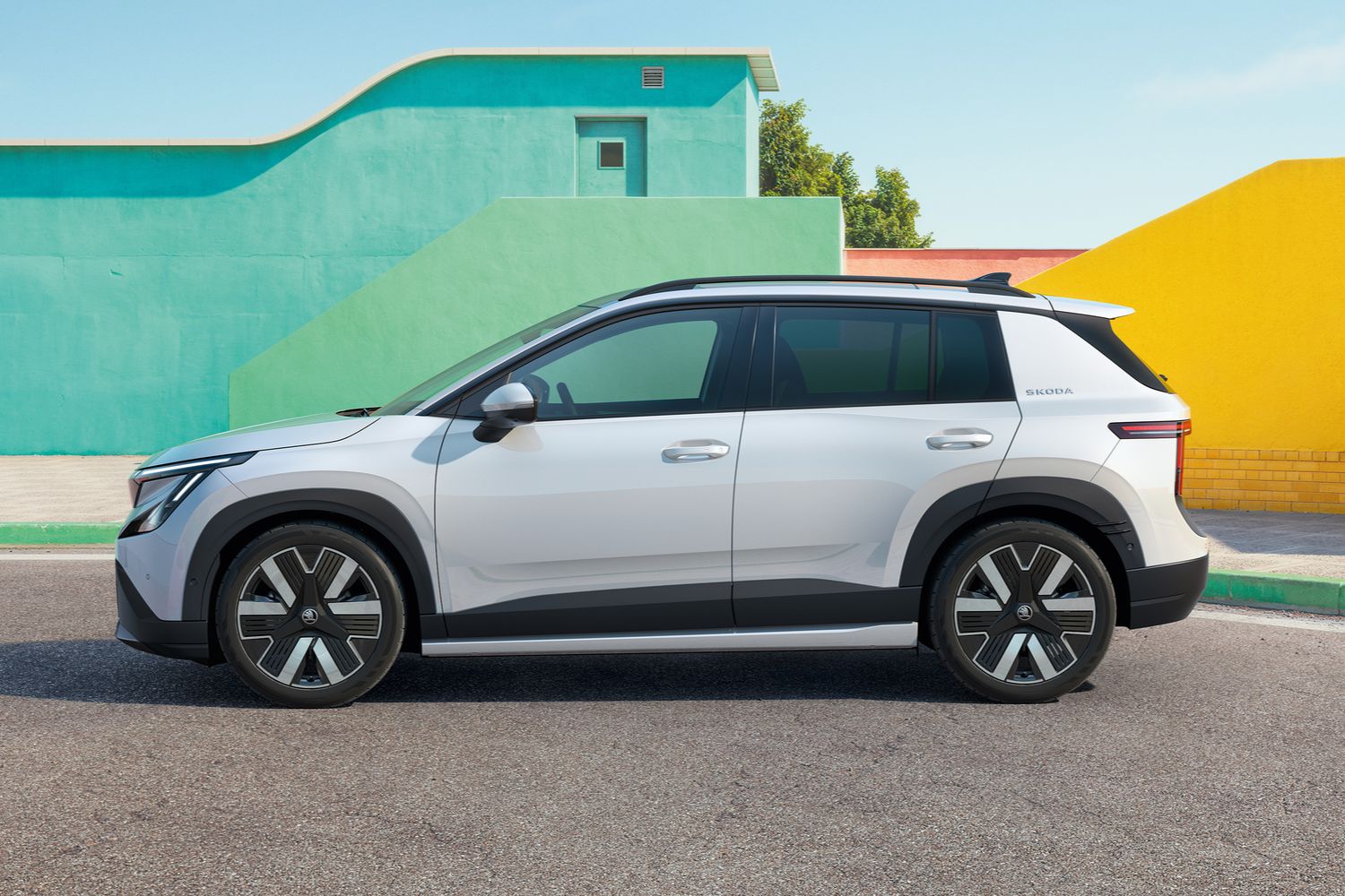 Side view of the Skoda Epiq, in white. Parked by a colourful pastel building.