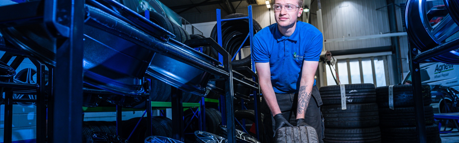 Agnew Repair Centre Specialist Technician holds tyre for Alloy Wheel Refurbishment
