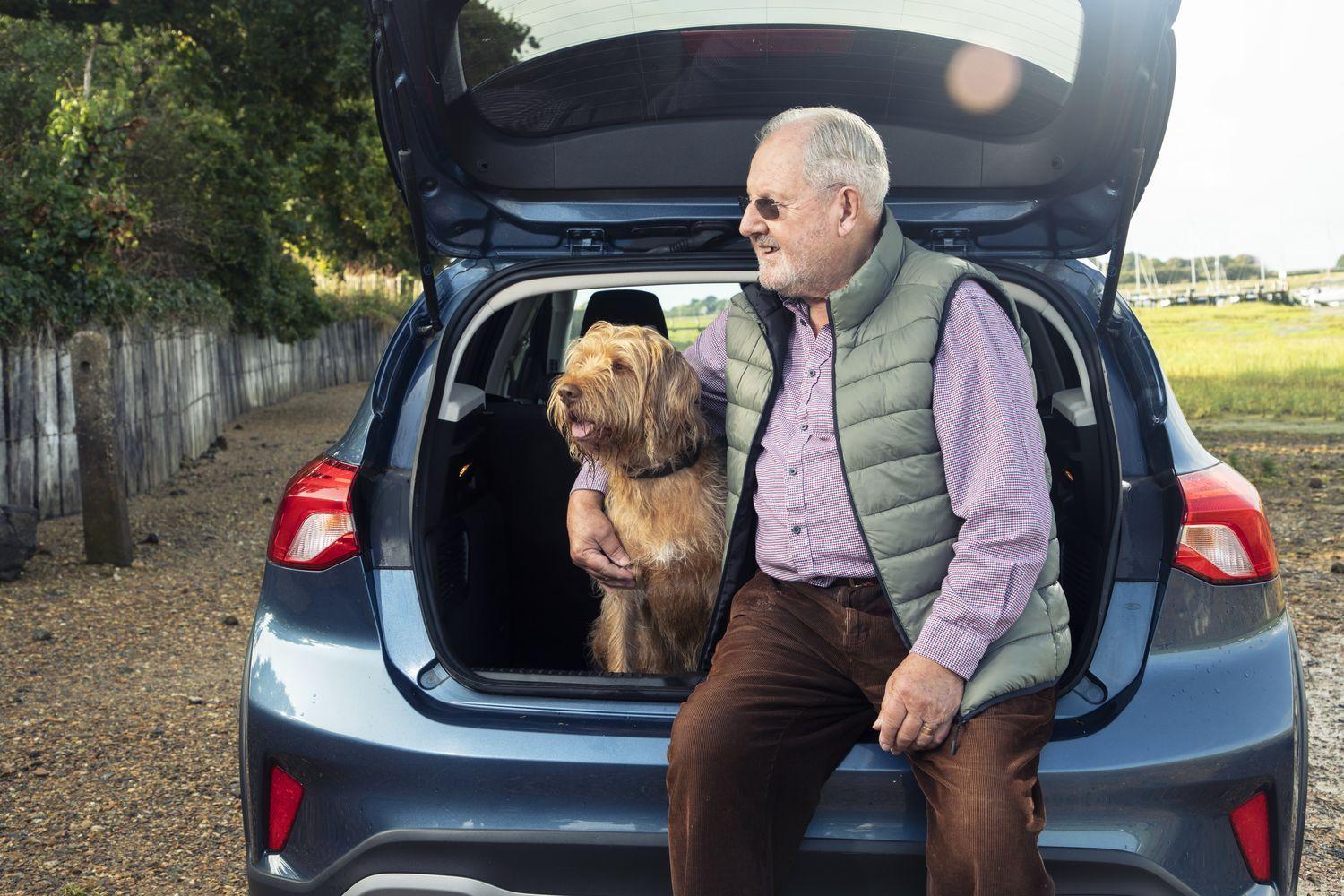 Man with dog sits in the back of his Motability car